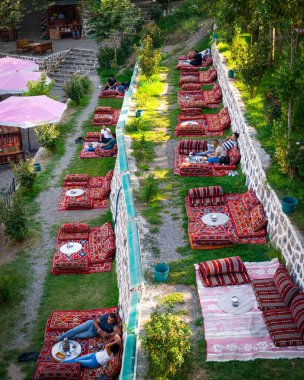 Diyarbakır, Türkiye - 17 Eylül 2020: Halk, Dicle Nehri üzerindeki tarihi köprü Ten Eyed Köprüsü 'nün (On Gozlu Kopru in Turkish) yanındaki doğu tarzı kafe restoranının keyfini çıkarıyor.