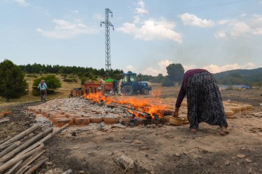 Mihaliccik, Eskisehir / Türkiye-26 Temmuz 2020: Kadın işçi kil çömlekleri ateşte kurutuyor.