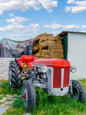Arka planda antika kırmızı traktör ve saman balyasının seçici odak noktası. Vintage köy yaşam tarzı.