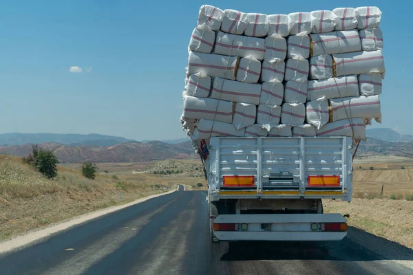 Back (rear) view of truck full of hay bales in traffic