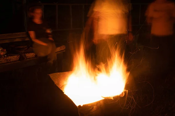 Camping fire and blurred people around