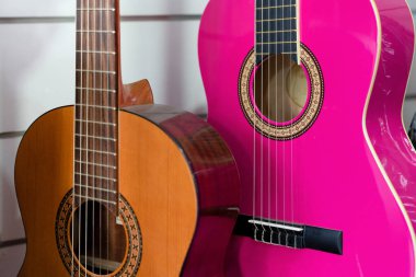Bir müzik dükkanında satılık kahverengi ve pembe gitarların seçici odak noktası.