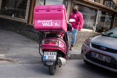 Ankara / Türkiye - 04 Mayıs 2020: Gıda dağıtım motosikleti ve kuyruk kutusuna yakından bakın. Arka planda motosikletçi.