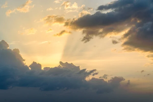 Dramatic black and red clouds with sunbeam at sunset