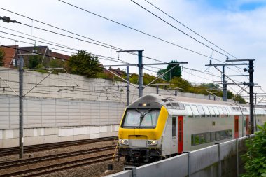 Tren raylarda, evlerin hemen yanında. Şehirdeki evler arasındaki demiryolu ve tren yolu, Brüksel, Belçika.
