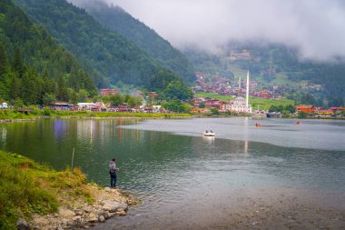 Trabzon / Türkiye - 07 Ağustos 2019: Uzungöl 'ün panoramik görünümü Türkiye' de turistik bir ilgi odağı. Uzungol 'da balıkçılık ve kürek tekneleri. Uzungol 'da balık tutmak.