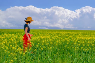 Konya, Türkiye-14 Mart 2019: Kırmızı gömlekli ve siyah pantolonlu genç kadın Konya lale tarlaları yakınlarındaki kanola sahasında