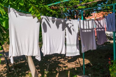 Çamaşırlar yazın dışarıda kurumak için güneşlenir, ağacın altında kısmen gölge altında.