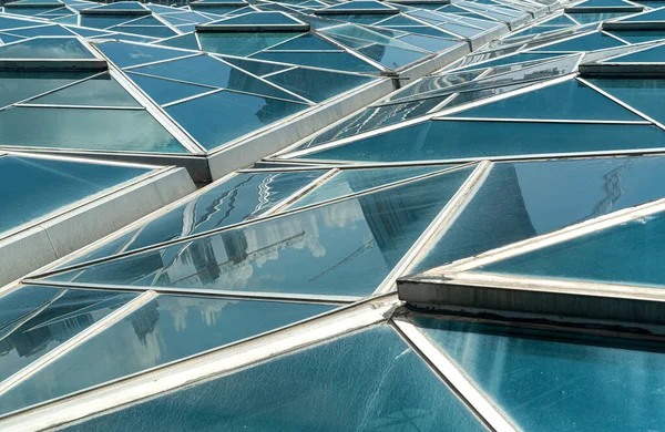 Windows. Transparent ceiling, roof or wall with generic glass units. Backlit structural glazing. Close-up of modern architecture fragment. Abstract geometric background with triangular pattern.