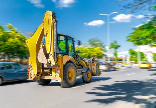 Kazıcı, mavi gökyüzü ve arka planda yeşil ağaçlarla yoğun trafiği olan Ankara ve Türkiye 'de hızlı sürüyor veya gidiyor