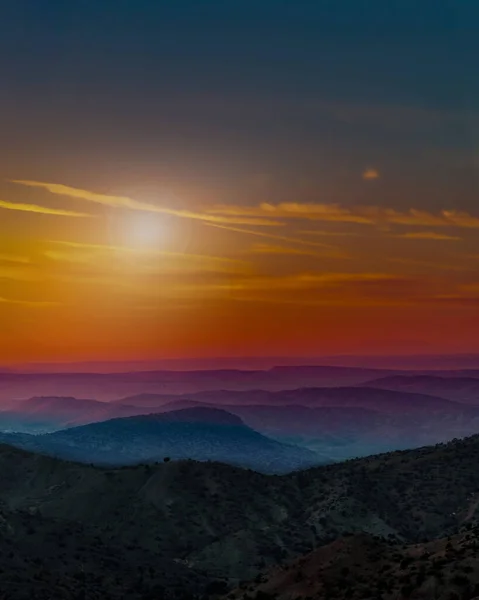 Landscape with orange and purple silhouettes of mountains, hills and forest