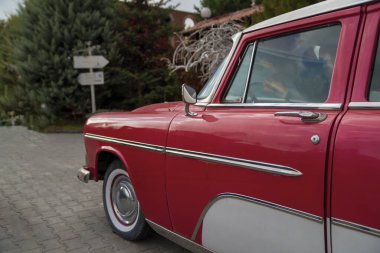 Bahçede kırmızı klasik bir araba parkı..