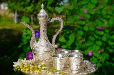 Arka planda eski sürahi ve gümüş ve yeşil yapraklardan yapılmış gözlük