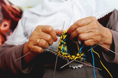 Örgü iğneleriyle renkli yün çoraplar ören yaşlı kadınların ellerine yaklaş.
