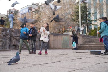 Ankara / Türkiye-3 Mart 2018: Çocuklar güvercinleri besliyor ve Ankara şehir merkezi Kizilay 'de günün tadını çıkarıyor