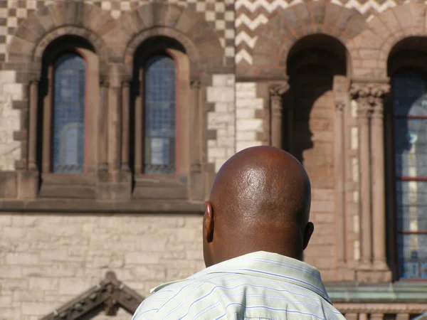 Back view of a well-shaven African American just in front of an old church in USA