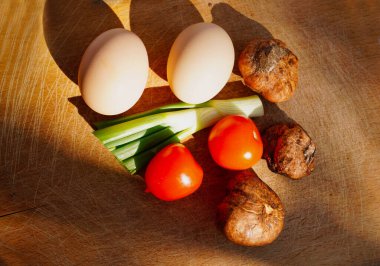 Beyaz mantarlar, yumurtalar, soğan, domatesler doğrama tahtasında