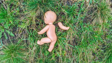 Kesik kollu küçük bir bebek yeşil çimlerin üzerinde uzanıyor. Saldırgan askeri çatışmalarda masum kayıp çocukların hayatı kavramı. Rusya 'nın Ukraynalı çocukların öldürülmesi.