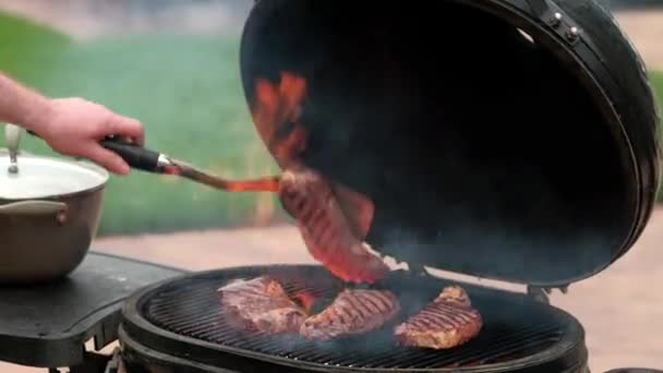 Barbecuing steaks on the grill. Future steak and barbecue. Meat in hand on the grill background. Meat eaters are not vegetarians. Weekend party. Food. Steak cooking process. Selective focus. — Stock Video