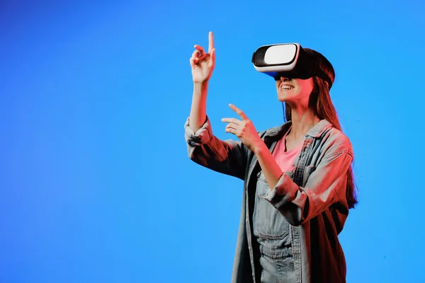 Lunettes de réalité virtuelle VR sur une fille. Il regarde vers l'avenir. Toucher le nouveau. Fantastique monde virtuel. L'émotion de l'immersion, la surprise, l'indignation, la peur, la peur, le rire, le plaisir. Concept de TVN. Image En Vente