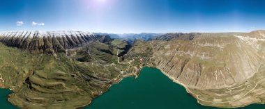 Lake Mochokh in the Republic of Dagestan, Russia. Snow-capped peaks top mountains in sunny weather. Gorge and ridges Kachta Ochlinski and Tanusdiril. Highlands. Vertical panorama. Travel in Dagestan. clipart