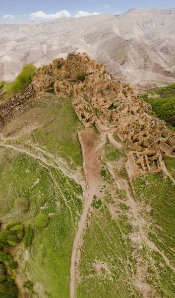 Une ancienne ville abandonnée est le village de Gamsutl au sommet d'une montagne au Daghestan. Une attraction populaire. vue du dessus depuis le drone. Panorama vertical. Photos De Stock Libres De Droits