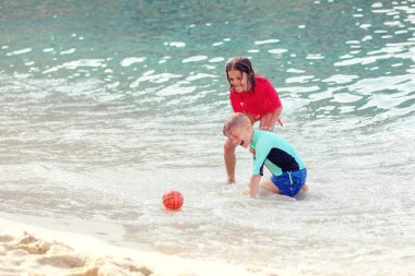 Oğlan ve kız okyanus sahilinde yaz tatili boyunca suda oynuyorlar.