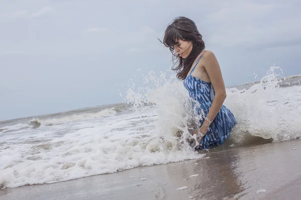 Modelo femenino sentado en la playa del océano salvaje — Foto de Stock