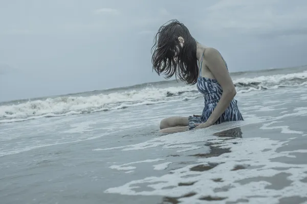Молодые женщины сидят в одиночестве в диком океане Стоковое Изображение
