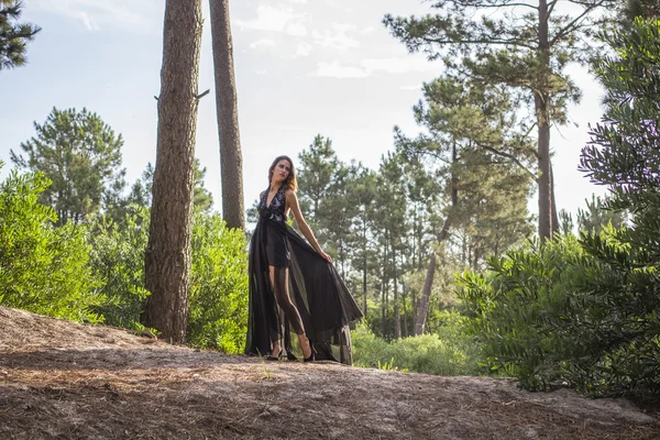 Mujeres jóvenes en negro vestido de noche solo en el bosque — Foto de Stock