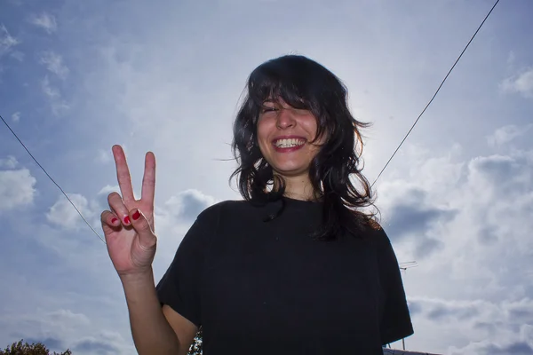 Menina sorrindo com sinal de dedo de paz Fotos De Bancos De Imagens Sem Royalties