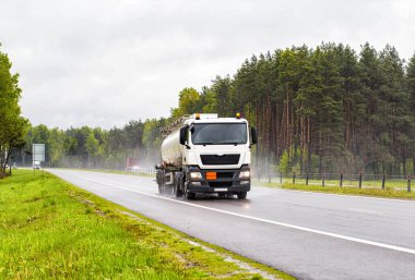 Patlayıcı maddelerin taşınması için özel bir araç yol boyunca seyahat eder ve yağmurlu havada petrol ürünleri taşır. Sanayi kavramı ve petrol ürünlerinin üreticiden tüketiciye taşınması. Farlar