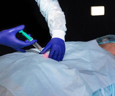 Doktor nörolog hastanın kalça eklemine tedavi edici bir ilaç enjekte ediyor. Artrosis ve eklem iltihabı tedavisi, yakın plan.