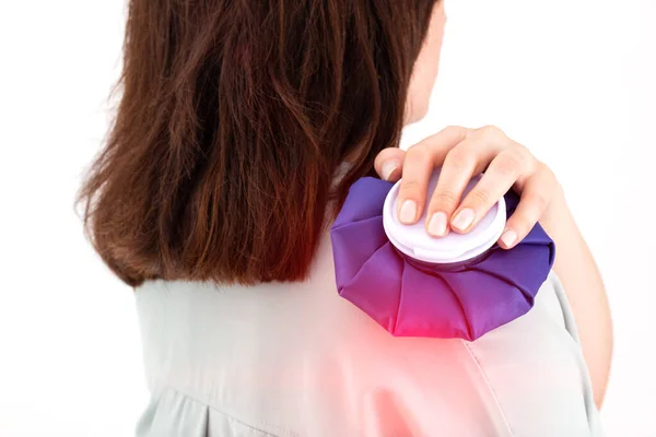 Uma menina segura um saco de gelo médico em sua articulação do ombro para dor e inflamação da articulação para reduzir o inchaço, close-up. Terapia — Fotografia de Stock