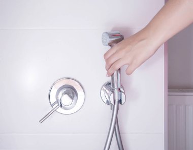 Bir kadının eli, yıkanmak ve özel yerlere bakmak için hijyenik duş alır, bidet. Yakın plan.