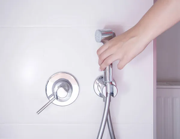 Uma mão de mulher toma um banho higiênico para lavar e cuidar de lugares íntimos, bidé. Close-up — Fotografia de Stock