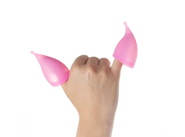 Dos copas menstruales se ponen en los dedos femeninos sobre un fondo blanco. Vasos vaginales higiénicos para recoger el flujo durante la menstruación, primer plano, aislar — Foto de Stock