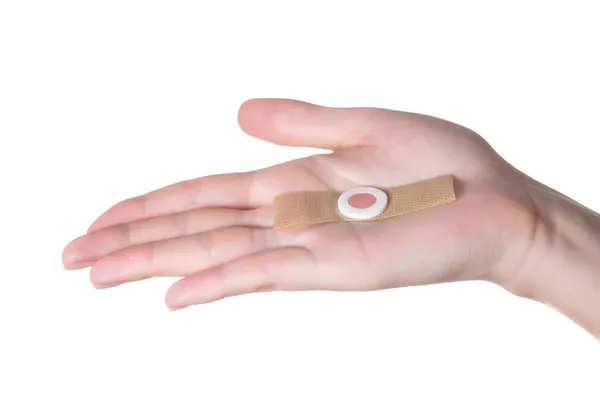 A womans hand holds a medical plaster against core calluses on the soles of the feet. Close-up, isolate — Stock Photo, Image