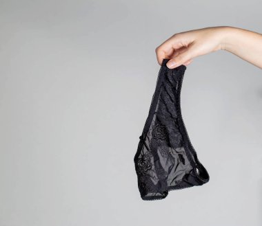 Kadın eli şık siyah kadın iç çamaşırları tutuyor. Kadın libidosu ve cinsel dürtü kavramı, kadın orgazmı. Zina, metin için kopyalama alanı