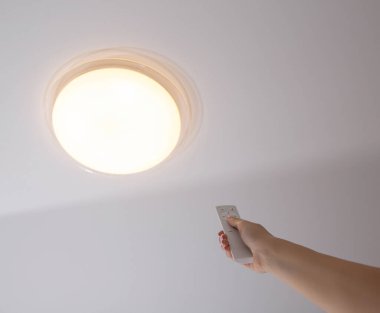Kontrol paneli kapalı modern LED tavan avizesi. Odadaki ışığın parlaklığını ayarlıyorum.