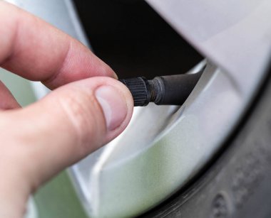 Bir adam arabanın tekerlek vanasını çeviriyor, yakın plan, nakliye.