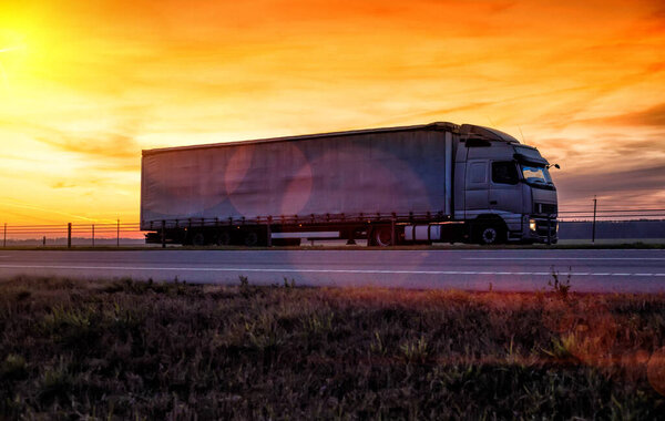 A beautiful truck with a trailer against the backdrop of an evening sunset before night. The concept of work and rest regime for truck drivers. Fine for breaching rules, tachograph
