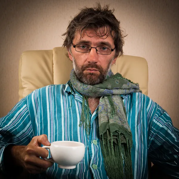 Sick man sitting in chair with cup — Stock Photo, Image