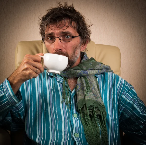 Sick man sitting in chair with cup — Stock Photo, Image