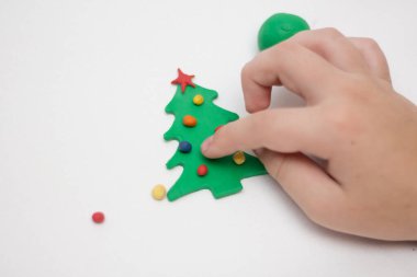 Child makes a toy tree from plasticine clipart