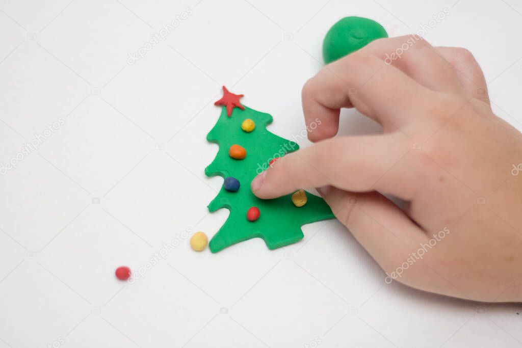 Child makes a toy tree from plasticine