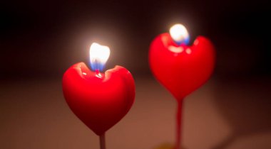 Two candles in the form of a heart. Are burning.
