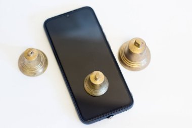 Copper bell on top of a cell phone.