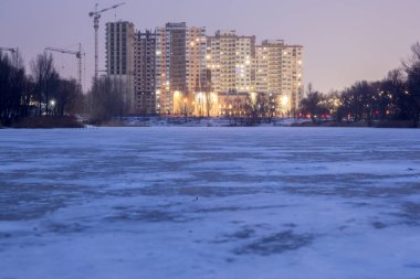 Kiev 'de yüksek binaların yakınında buzla kaplı bir göl.