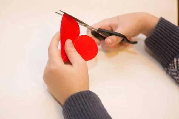 Kind Snijdt Een Hart Voor Valentijnsdag Een Witte Achtergrond — Stockfoto